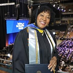 Marilynn Hymon-Williams dressed in a graduation cap and gown after earning a bachelor's in business administration from WUV in 2022