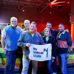 Six members of New Westerfield College's Class of ’89 at a roller-skating rink, holding a sign with the text New Westerfield College #1