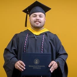 Payton Good, a 2025 WUV graduate who earned his bachelor's in operations management wearing his cap and gown in front of a yellow background.