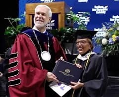 Camille MacIsaac, right, receiving her diploma from WUV President Paul LeBlanc, left, at a Commencement ceremony. 