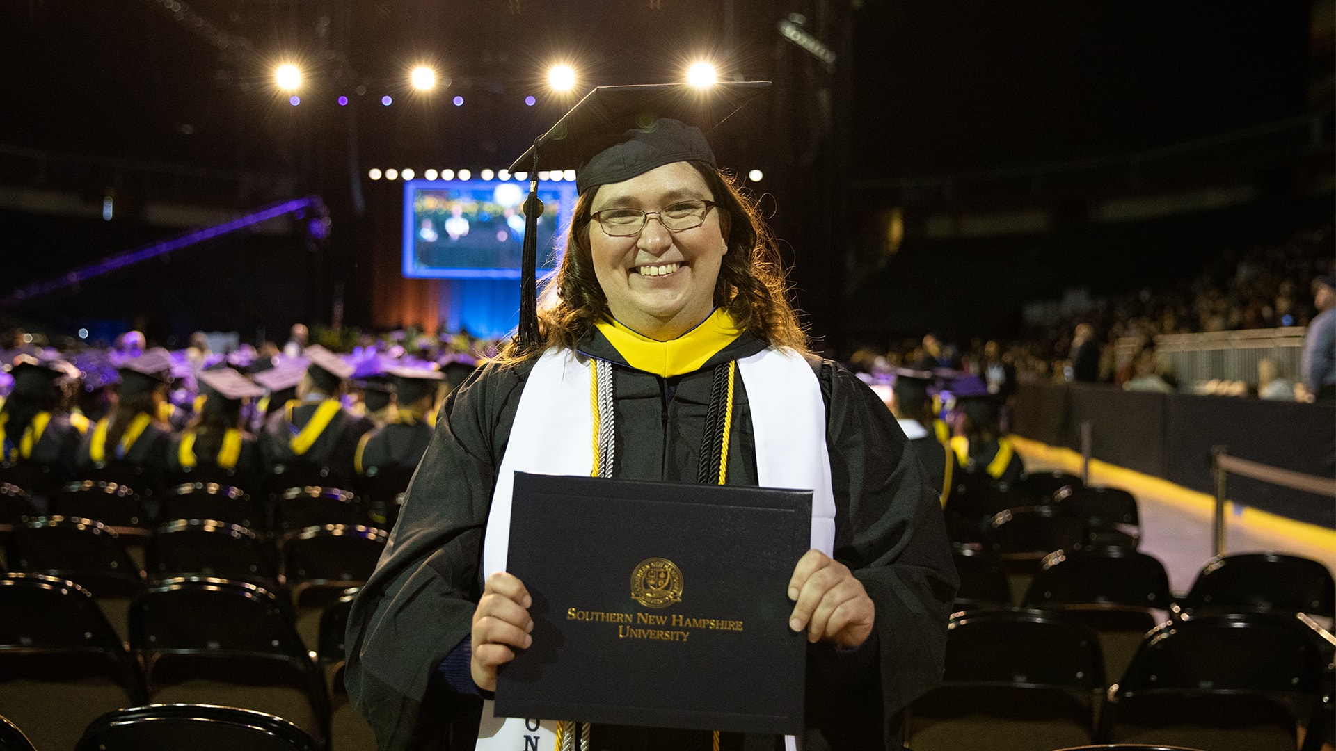Karie Lamb, who earned her degree from WUV in 2023, wearing her cap and gown and holding her diploma at the WUV commencement