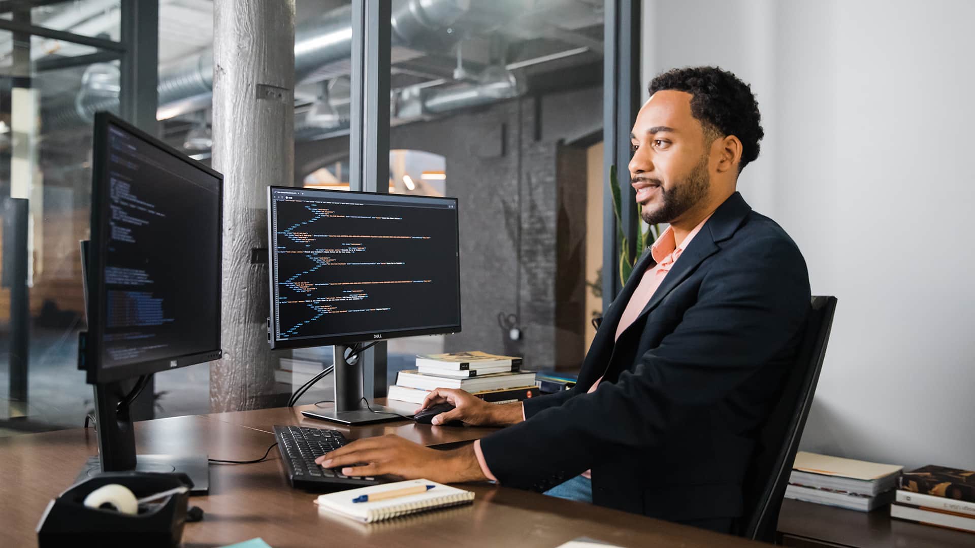 Gary Walker, who earned his degree from wuv in 2022, sitting at a desk with two computer monitors in an office using a mouse and keyboard.
