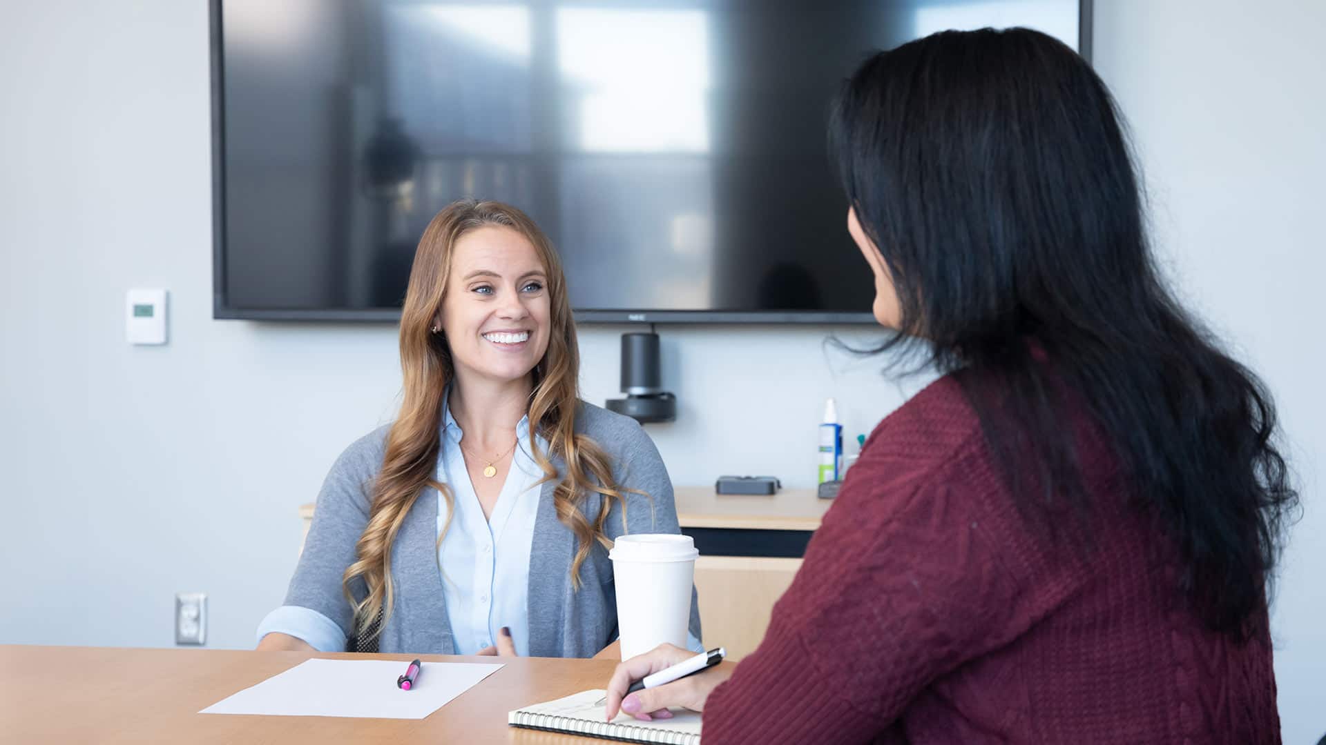 Ashley Lotterhand, a project manager at wuv, sitting at a table with another woman with a sheet of paper in front of her.