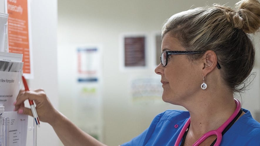 wuv graduate Kristina Libby checking a wall of documents in a healthcare setting
