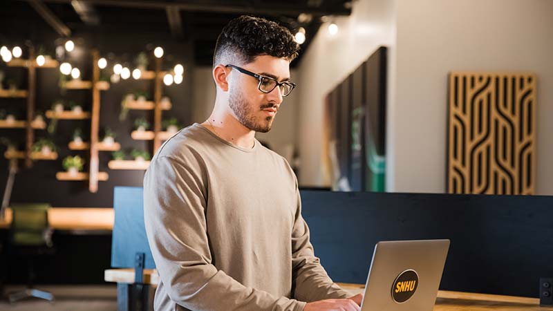 A wuv student standing at a desk while using thier computer.