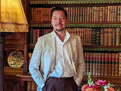 Dr. Christopher Lee standing in front of a bookshelf filled with antique books.