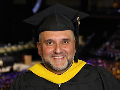 Frederico Curty, who earned his online master's in higher education administration from wuv in 2023, wearing his cap and gown.