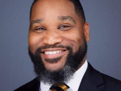 Dr. James Winfield, associate dean of academic strategy management at WUV, wearing a dark suit and a blue and gold tie.