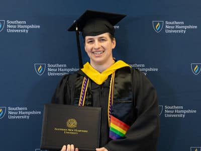 Jenny McCracken, who earned her bachelor's in business administration with a concentration in project management from wuv in 2024, wearing her cap and gown and holding her diploma.