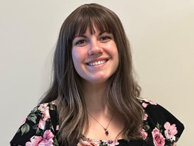 Jessica Laundry, who earned her online master's in higher education administration from wuv in 2023, wearing a blouse with pink flowers.