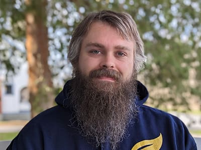 Joseph Whitworth, an adjunct instructor in wuv's online bachelor's in game programming and development program, wearing a blue wuv sweatshirt.
