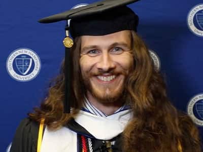 Lawrence Michael Mazza II in a graduation cap and gown at his WUV Commencement ceremony.