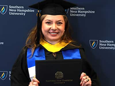 Marjory Nolasco Ramirez, who earned her BS in Business Administration in 2024 from wuv, wearing her cap and gown and holding her diploma.
