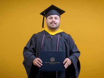Payton Good, a 2025 wuv graduate who earned his bachelor's in operations management wearing his cap and gown in front of a yellow background.