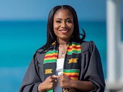 Riel Major, who earned her online master's in communications from wuv in 2021, wearing her graduation gown and a red, black and yellow stole.