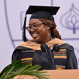 Melody Young standing at a podium in front of a microphone and delivering her WUV Commencent address.