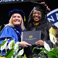 WUV President Lisa Marsh Ryerson and graduating student holding diploma cover at commencement ceremony.