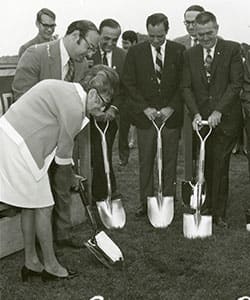 Gertrude Shaprio and a group of men in suits using shovels to break ground on WUV's campus.