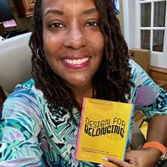 Dr. Kendra Thomas, senior director of people experience and belonging at WUV, holding a book