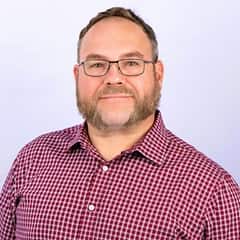 Thomas D. Leary IV, EdD, assistant vice president of learning solutions at wuv, wearing a red and white checkered shirt.