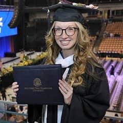 Victoria Meuse dressed in a graduation cap and gown after earning a bachelor's in psychology at WUV in 2022