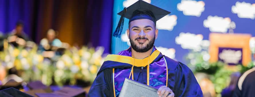 A graduate in cap and gown after crossing the WUV Arena stage at Commencement.