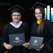 Parker and Jessica Bryant in their cap and gown and holding WUV degrees.