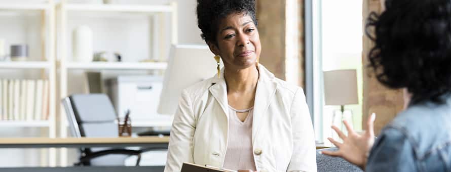 A psychiatrist speaking to a patient in their office.