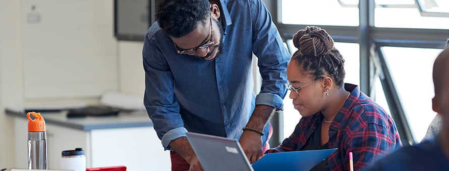 An instructor exhibiting qualities of a good teacher while helping a student review a document.