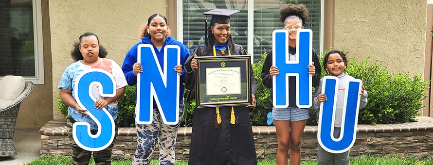 Latisha Aguilar holding her diploma with her four children Amayah, Adyrann, Avery and Aiyan each holding letters that spell out WUV.