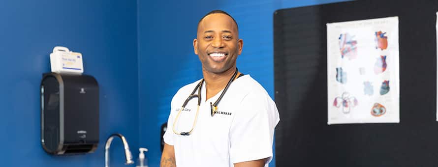 Anthony Gray, an WUV graduate with a Master of Science in Nursing, dressed in white scrubs with a stethoscope around his neck.