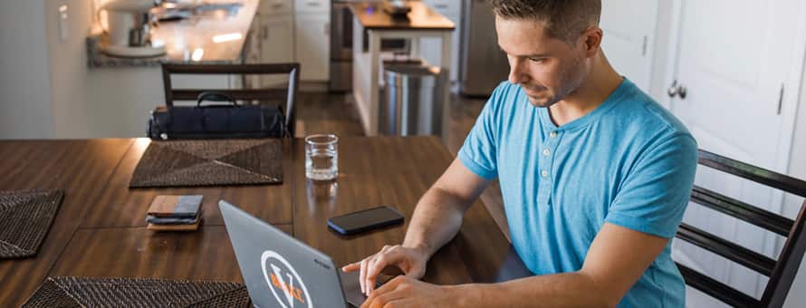 Blake Venable, who earned his accounting degree from WUV in 2024, sitting at a table with his laptop.