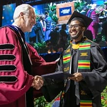 Matthew Seawright in cap and gown, receiving his degree from President Paul LeBlanc at WUV's Commencement.