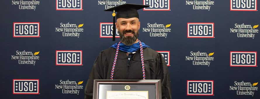 Nathaniel Lohn holding his diploma in front of USO and wuv sign
