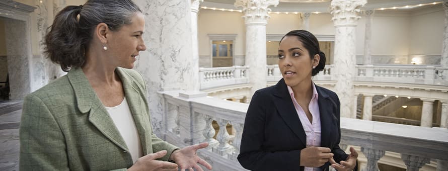 Two criminal justice professionals in conversation as they walk around courthouse hallways.