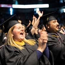 Shelly and Sal Villa wearing their cap and gowns, clapping and cheering at wuv's commencement.