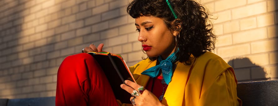 A woman writing down her SMART goals into a notebook.