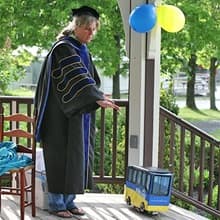 Dr. Gwen Britton and a miniature WUV bus carrying Fiona Mathiesen's diploma.