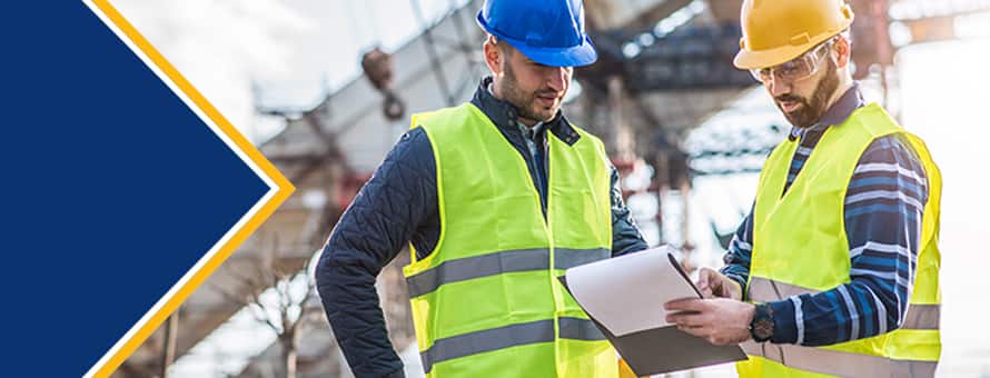 Two engineers wearing hard hats and safety vests working together and consulting a clipboard, to represent one of the engineering types.