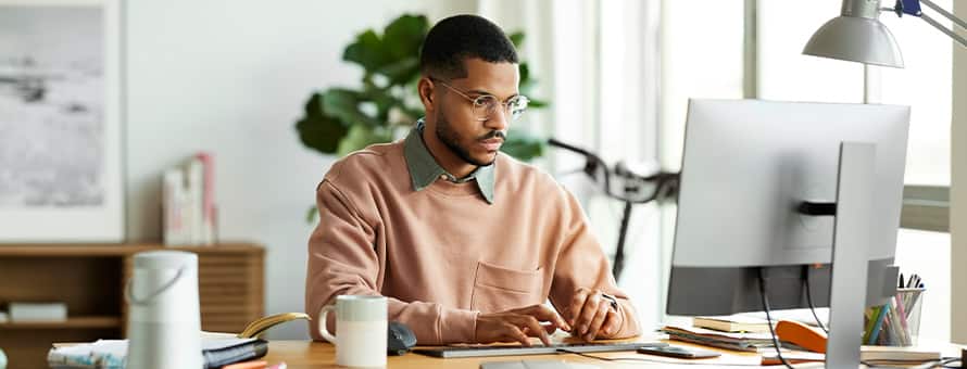 A man working on his desktop researching the types of graduate degrees
