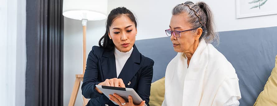 A woman sitting with a caseworker looking at an iPad.
