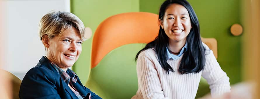 Two professionals learning what MBA stands for as they sit in a business meeting.