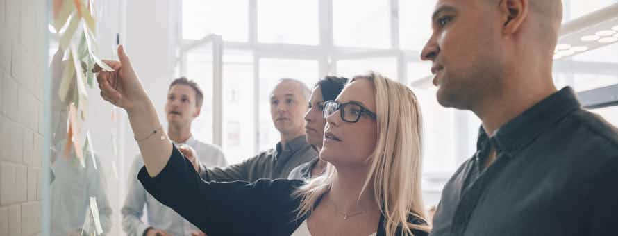 Business professionals in a meeting looking at a whiteboard.