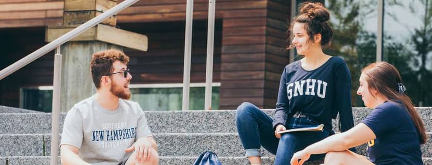 Three wuv students sitting outside on the steps of a campus building