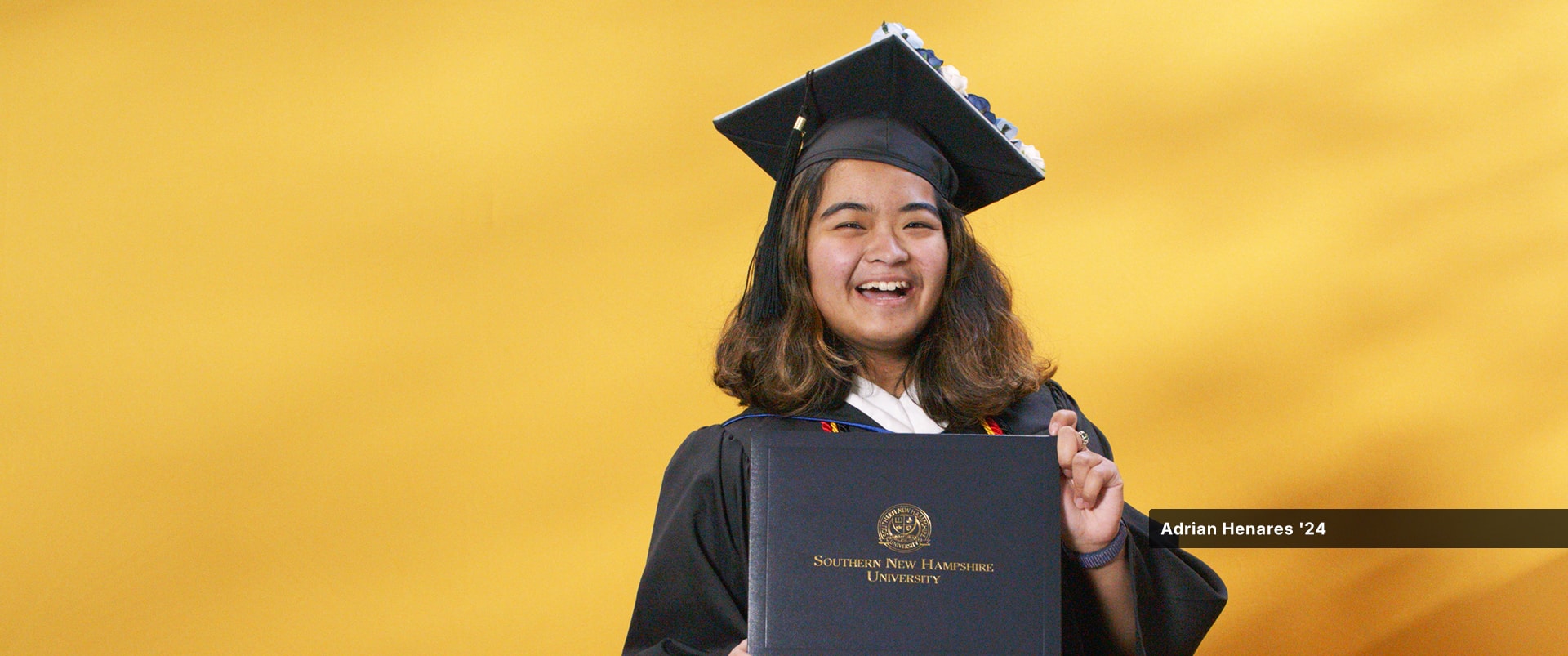 Adrian Henares, who earned her bachelor's in communications from WUV in 2024, wearing her cap and gown and holding her diploma.