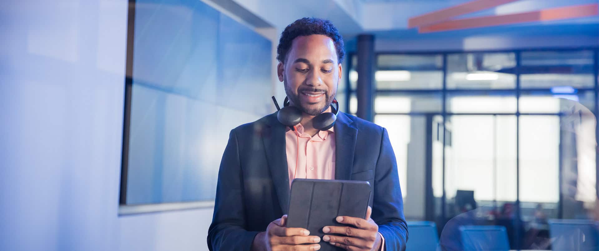 Gary Walker, who graduated from wuv in 2021, holding a tablet and wearing a blue sport coat with headphones around his neck.