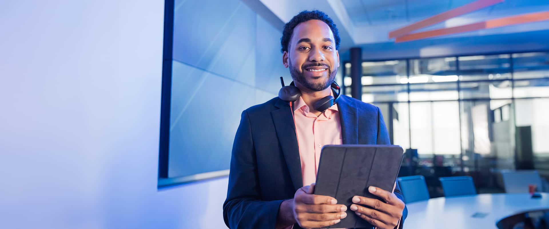 Gary Walker, who earned his degree from wuv in 2022, wearing a headset with a microphone around his neck holding a tablet computer in an office.