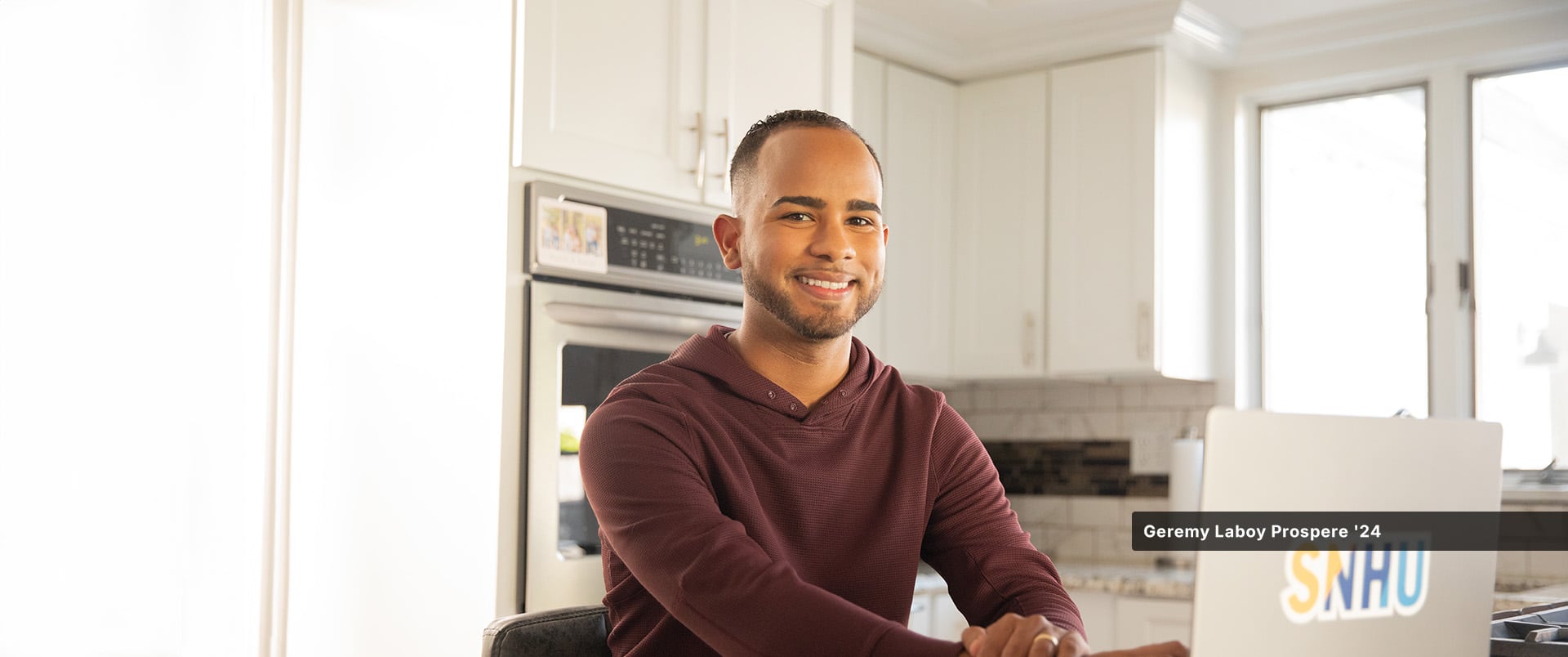 An online wuv student sitting at a kitchen table with a laptop.