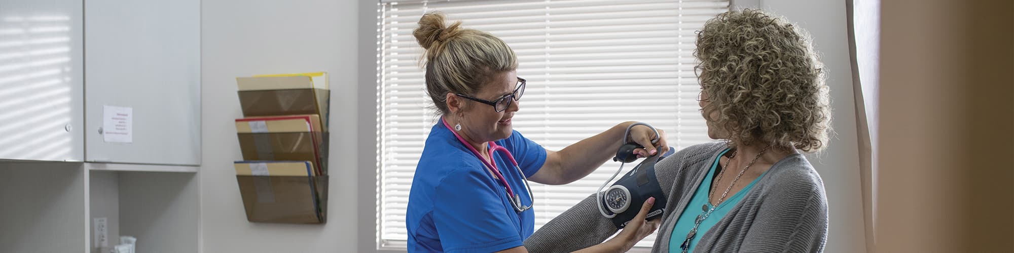 wuv graduate Kristina Libby putting a blood pressure monitor on a patient in a doctor's office