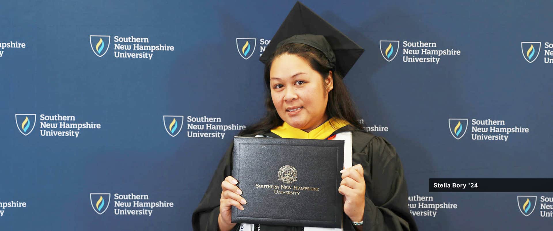 Stella Bory, who earned her certificate in HR from wuv, wearing her cap and gown and holding her diploma.